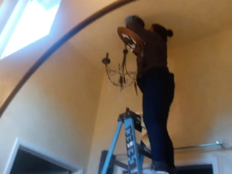 Electrician installing a chandelier in a Newman residence